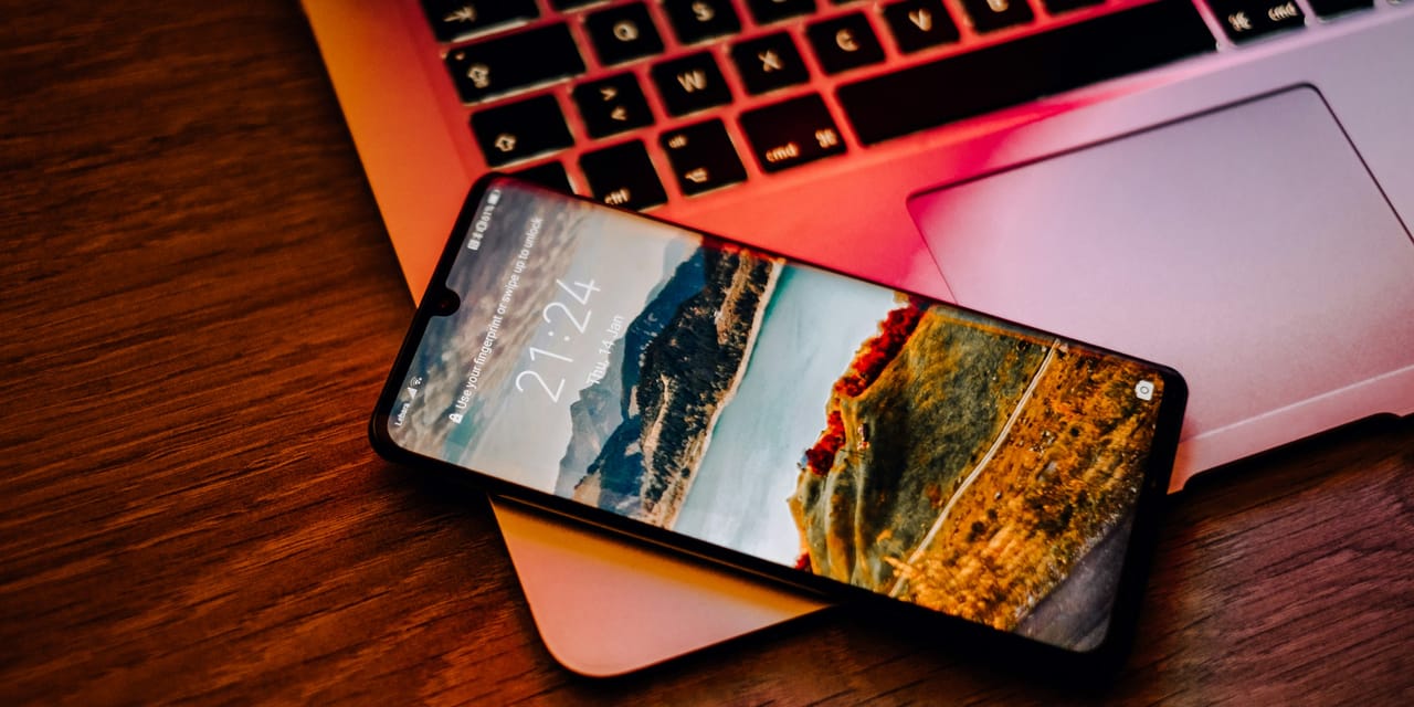 Telefon cu ecranul de blocare asezat pe un laptop, ca simbol al autentificarii digitale